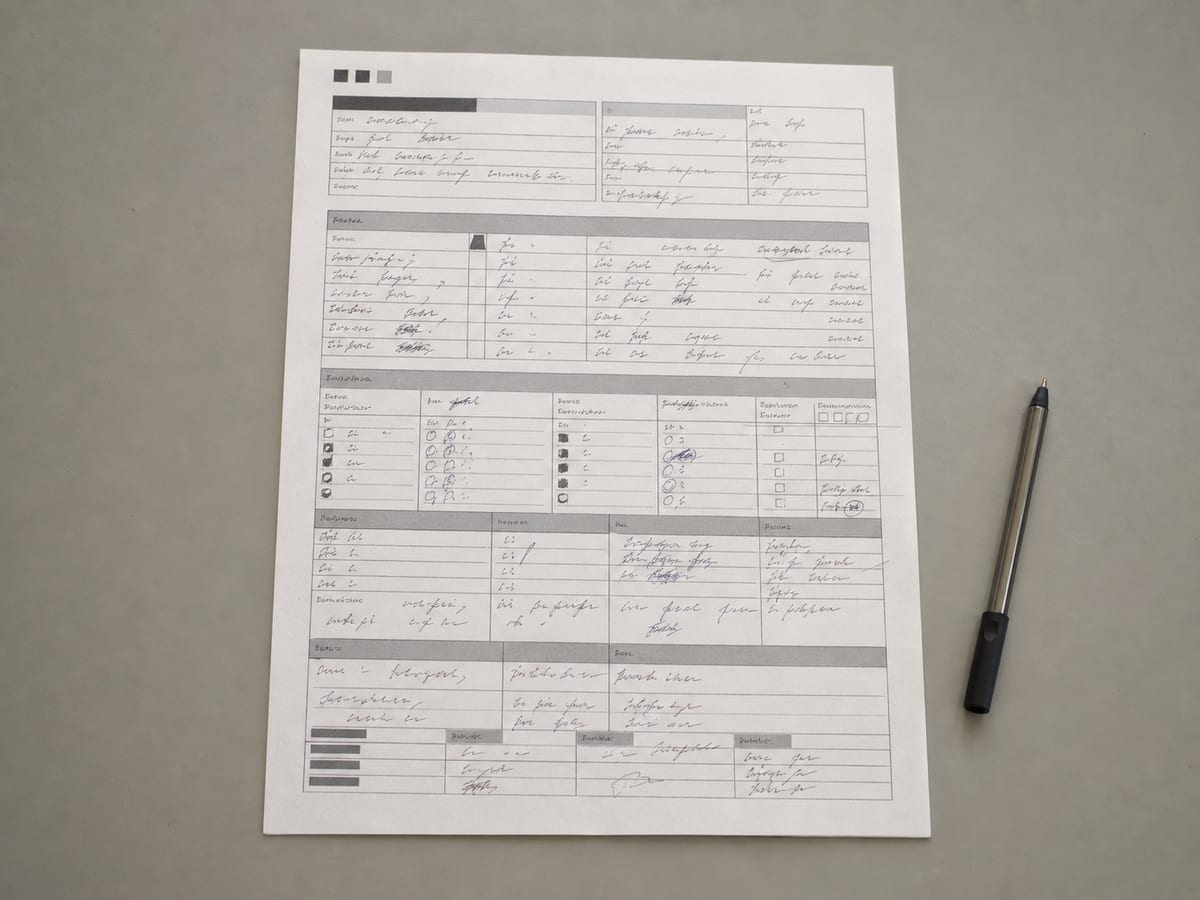 A printed one-page fact sheet on a desk with ruled fields filled in by hand, a pen resting in the margin