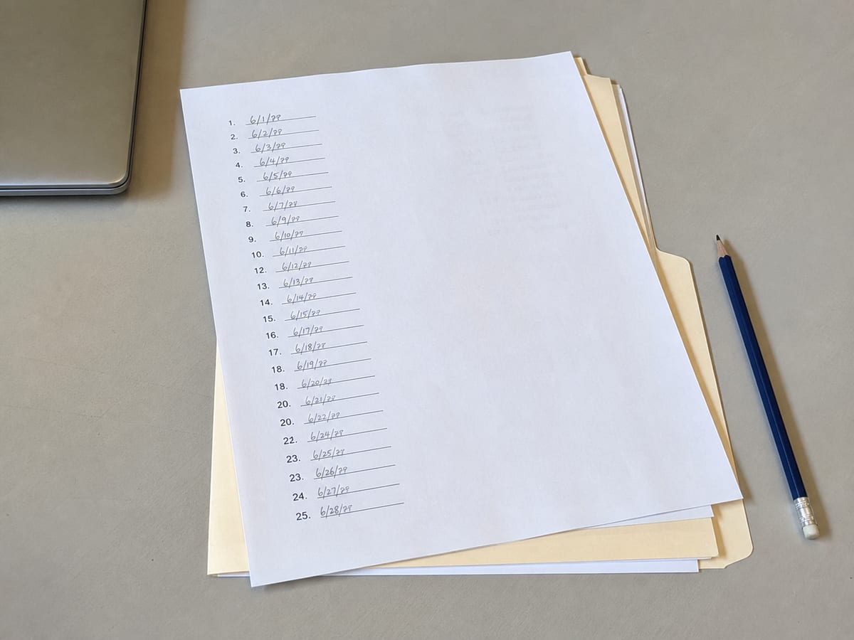 A printed sheet of numbered questions on a desk, each with a handwritten date beside it, a plain folder underneath