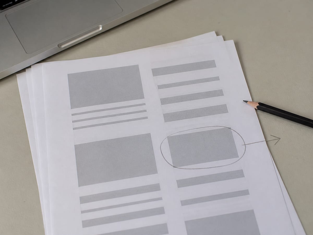 A printed page where several blocks are solid grey rectangles instead of text, one of them ringed in pencil with an arrow drawn out to the margin