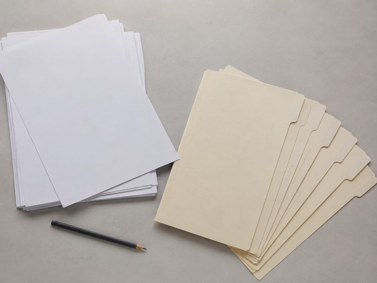 A set of tabbed dividers laid out flat in a fan on the desk, separated from the binder, each tab blank