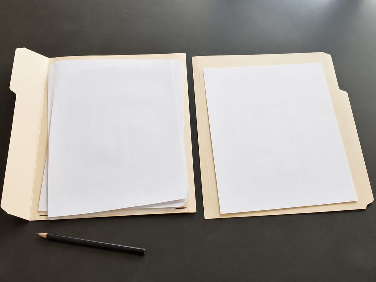 Two paper folders laid open side by side on the desk, one holding a small sheaf of sheets and the other holding a single sheet