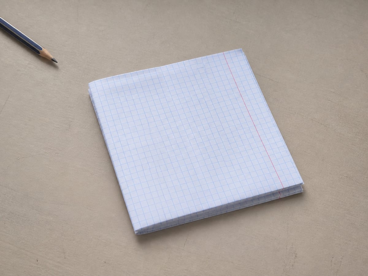A single sheet of ruled analysis paper on the desk folded neatly into quarters, reduced to a manageable size, resting squarely