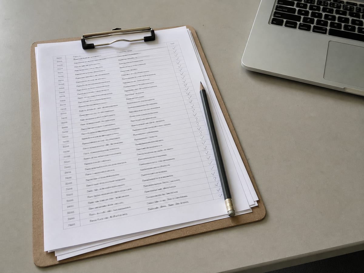 A printed inventory list on a clipboard with a column of handwritten ticks and question marks against each row