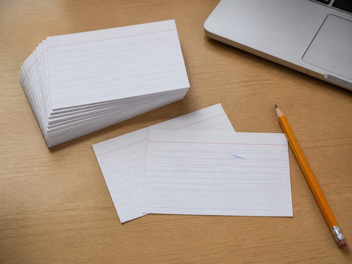 A set of index cards spread on a table, a few pulled forward from the rest, a pencil resting beside the selected group